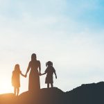 Silhouette of mother with her daughter standing and sunset